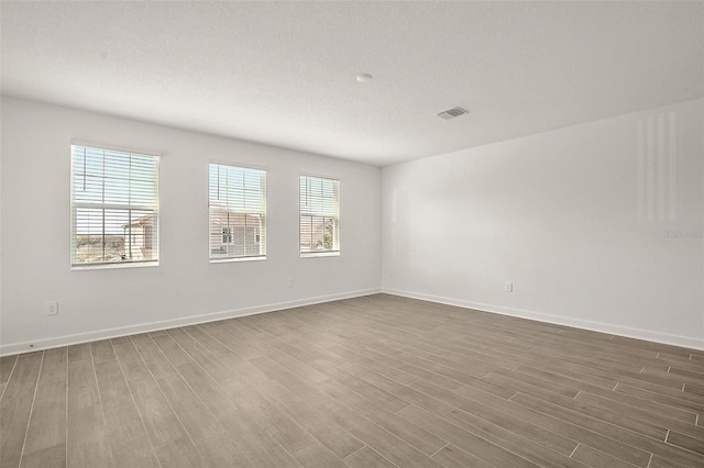 unfurnished room featuring dark wood-type flooring and a textured ceiling