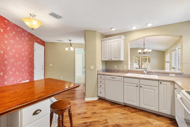 kitchen with white cabinets, white appliances, decorative light fixtures, and sink