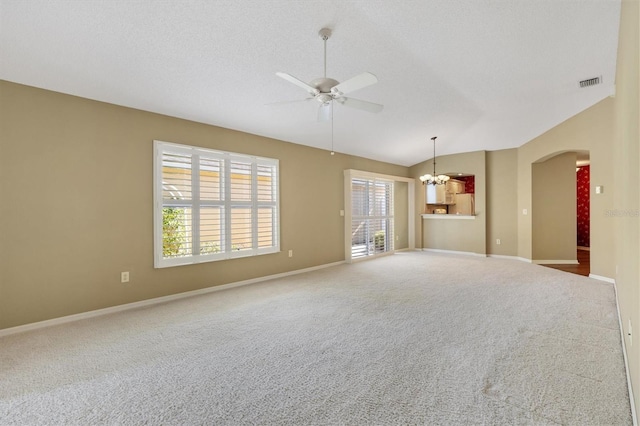 empty room featuring a textured ceiling, ceiling fan with notable chandelier, lofted ceiling, and carpet floors