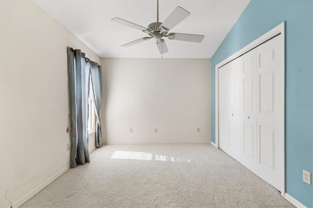 unfurnished bedroom featuring ceiling fan, a closet, light carpet, and a textured ceiling