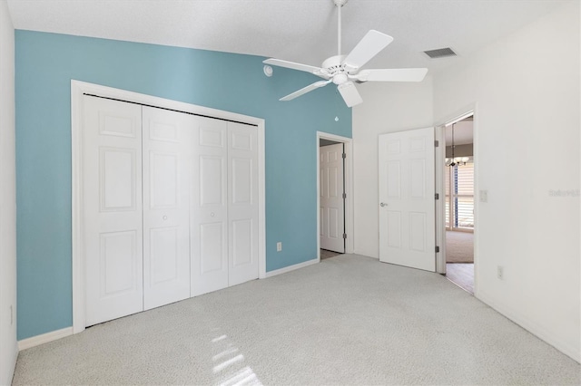 unfurnished bedroom featuring light carpet, ceiling fan with notable chandelier, vaulted ceiling, and a closet