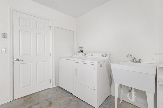 laundry area with washing machine and clothes dryer, sink, and a textured ceiling