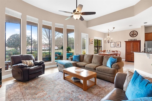 living room with light hardwood / wood-style floors and ceiling fan with notable chandelier