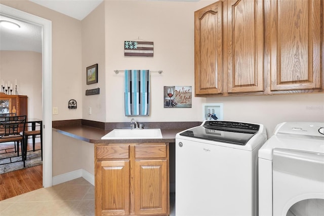 laundry area with light tile patterned flooring, cabinets, independent washer and dryer, and sink