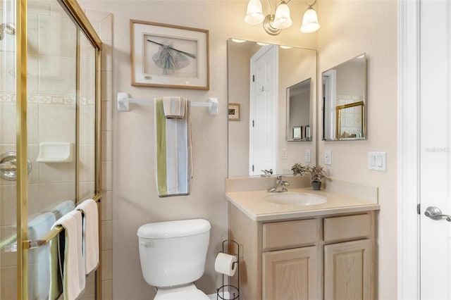 bathroom featuring vanity, toilet, and a shower with shower door