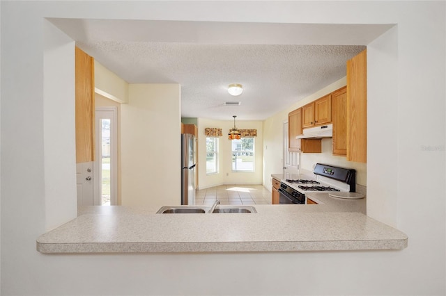 kitchen with stainless steel refrigerator, sink, a textured ceiling, light tile patterned floors, and white stove