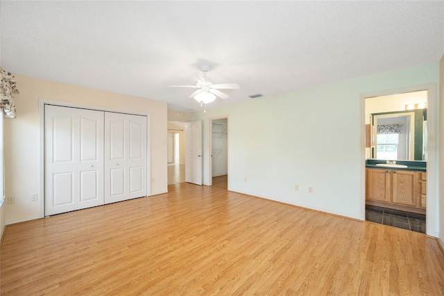 unfurnished bedroom with ceiling fan, connected bathroom, and light hardwood / wood-style flooring