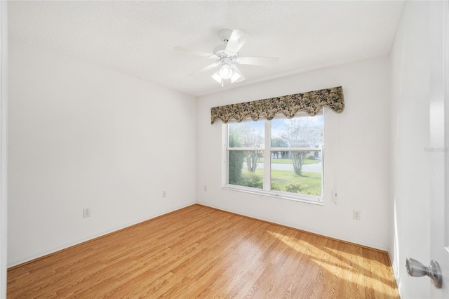 empty room featuring ceiling fan, light wood-type flooring, and a textured ceiling