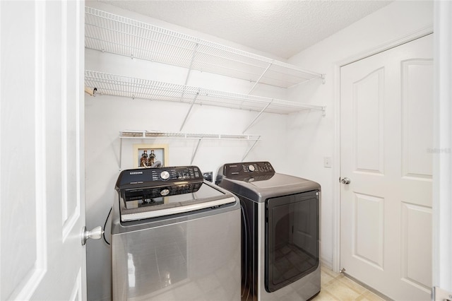 laundry area with washing machine and clothes dryer and a textured ceiling