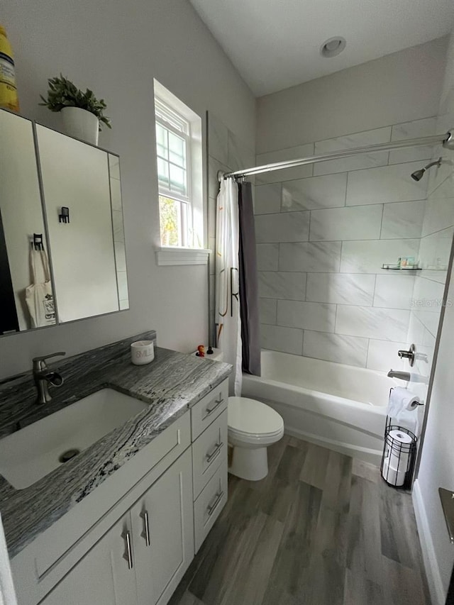 full bathroom featuring wood-type flooring, shower / tub combo with curtain, vanity, and toilet