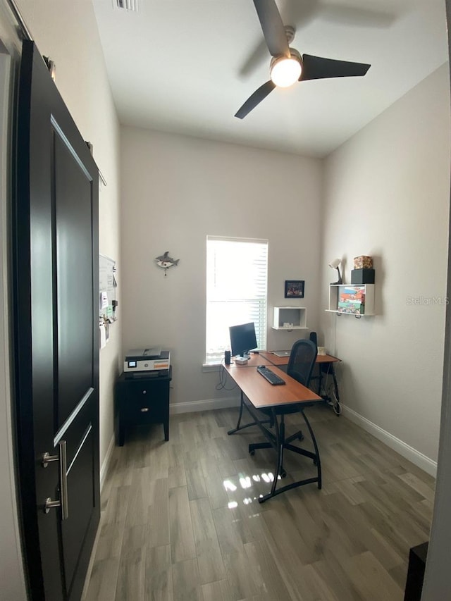 home office featuring wood-type flooring and ceiling fan