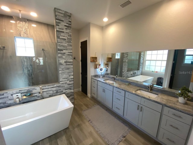 bathroom with tile walls, vanity, a notable chandelier, wood-type flooring, and independent shower and bath