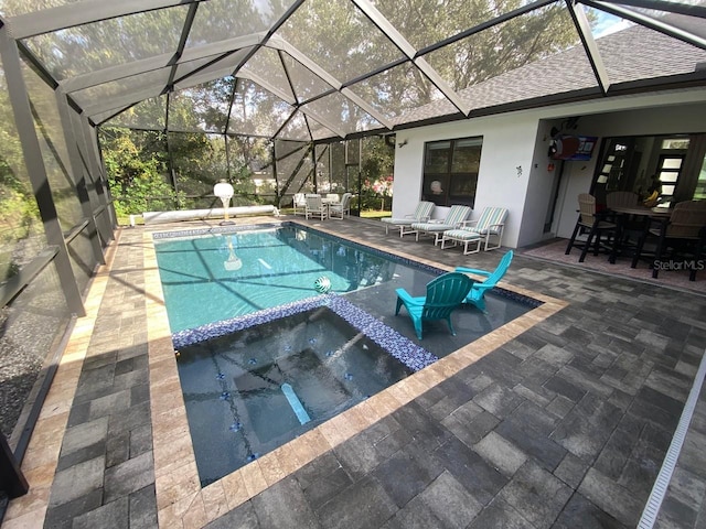 view of swimming pool with an in ground hot tub, a patio area, and glass enclosure