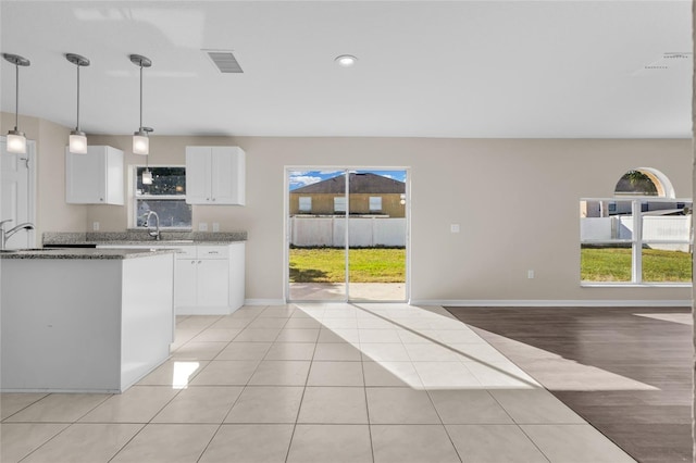 kitchen featuring light stone counters, sink, decorative light fixtures, white cabinets, and light tile patterned flooring