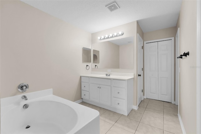 bathroom with tile patterned floors, vanity, a textured ceiling, and a tub