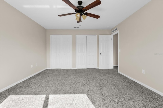 unfurnished bedroom featuring multiple closets, ceiling fan, and carpet