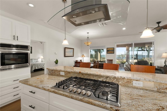 kitchen with pendant lighting, white cabinets, light stone countertops, and appliances with stainless steel finishes