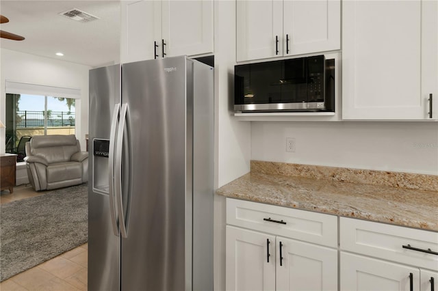 kitchen with light tile patterned flooring, light stone counters, white cabinetry, and stainless steel appliances