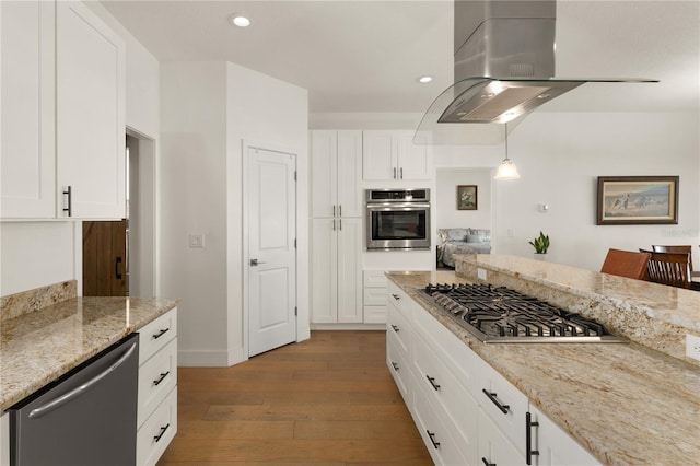 kitchen with pendant lighting, appliances with stainless steel finishes, light hardwood / wood-style floors, white cabinetry, and extractor fan