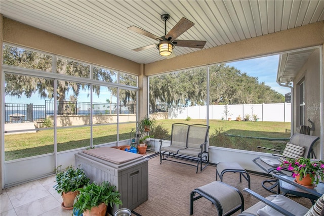 sunroom / solarium with ceiling fan and a water view