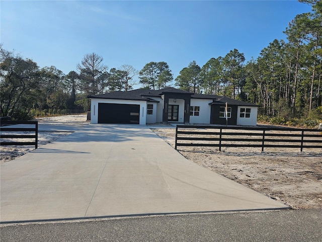 view of front of home featuring a fenced front yard, stucco siding, concrete driveway, and a garage