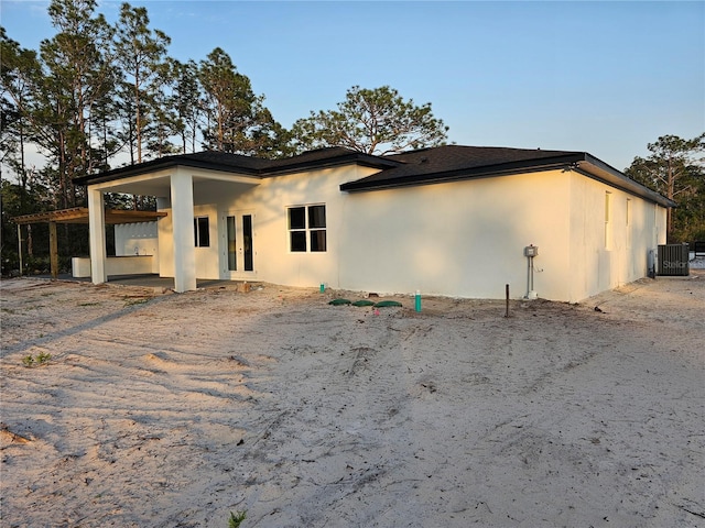 back of house featuring stucco siding and cooling unit