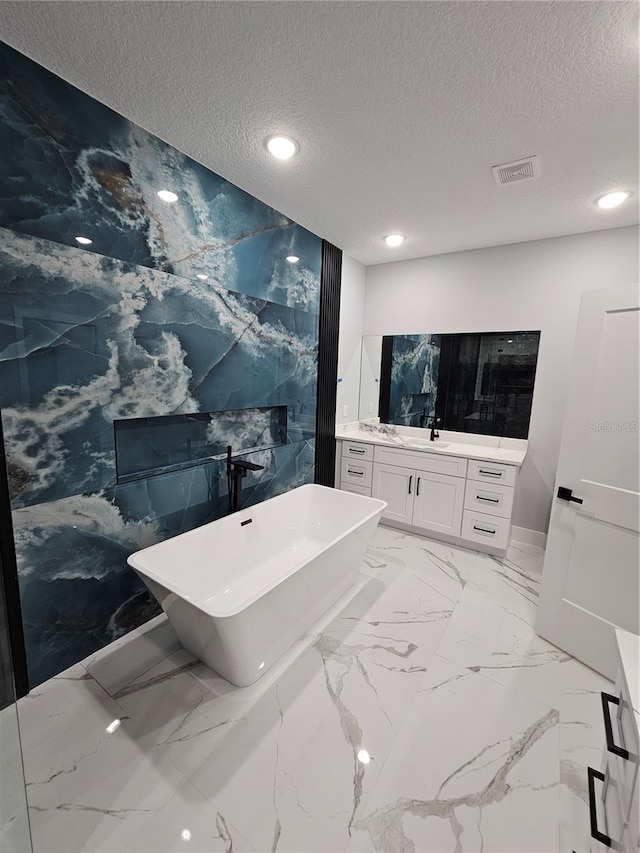 42157 Tamarac St, Eustis, FL 32736 - bathroom featuring vanity, a freestanding tub, a textured ceiling, recessed lighting, and baseboards
