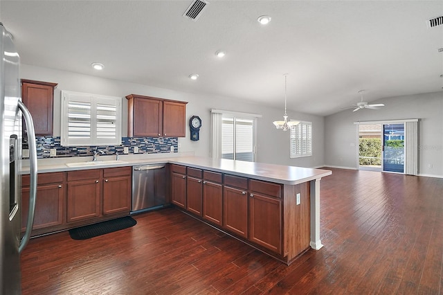 kitchen with sink, hanging light fixtures, stainless steel appliances, kitchen peninsula, and decorative backsplash