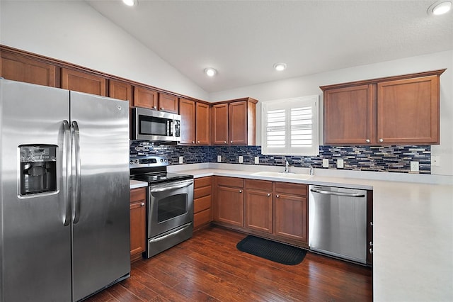 kitchen featuring sink, dark wood-type flooring, stainless steel appliances, vaulted ceiling, and decorative backsplash