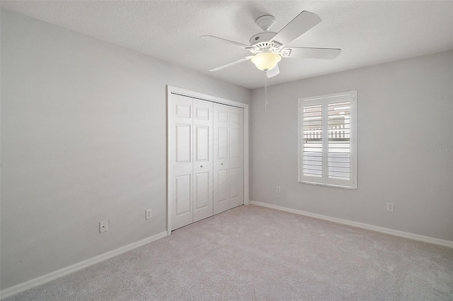 unfurnished bedroom with ceiling fan, a closet, and light colored carpet