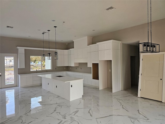 kitchen featuring visible vents, marble finish floor, and a center island