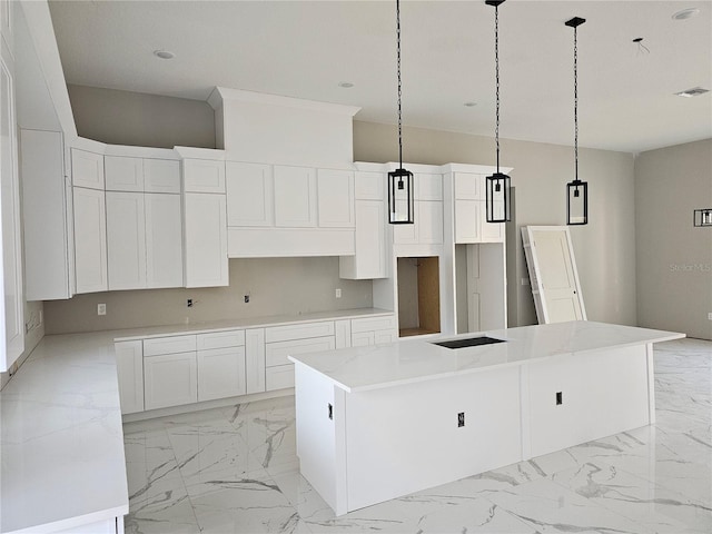 kitchen with white cabinetry, visible vents, marble finish floor, and a kitchen island