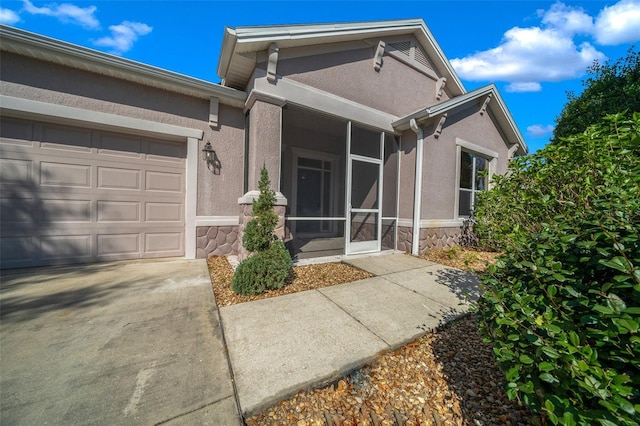 doorway to property featuring a garage, stone siding, and stucco siding