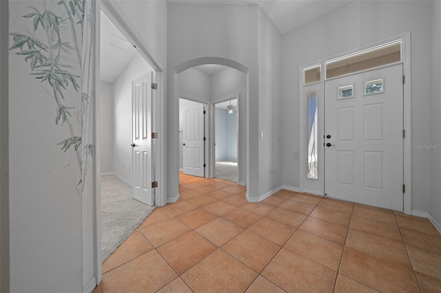 entrance foyer with arched walkways, light tile patterned floors, visible vents, and baseboards