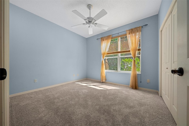 empty room with carpet floors, a ceiling fan, baseboards, and a textured ceiling