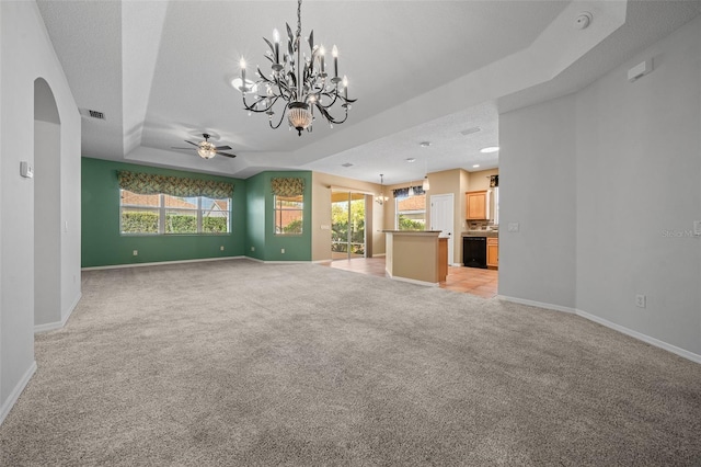 unfurnished living room featuring visible vents, baseboards, a raised ceiling, light colored carpet, and a wealth of natural light