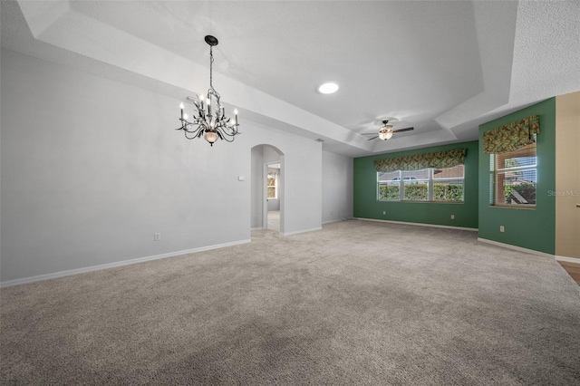 unfurnished room featuring carpet, baseboards, a raised ceiling, and arched walkways