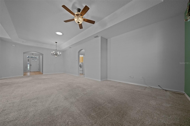 empty room featuring washer / dryer, arched walkways, a raised ceiling, and light carpet