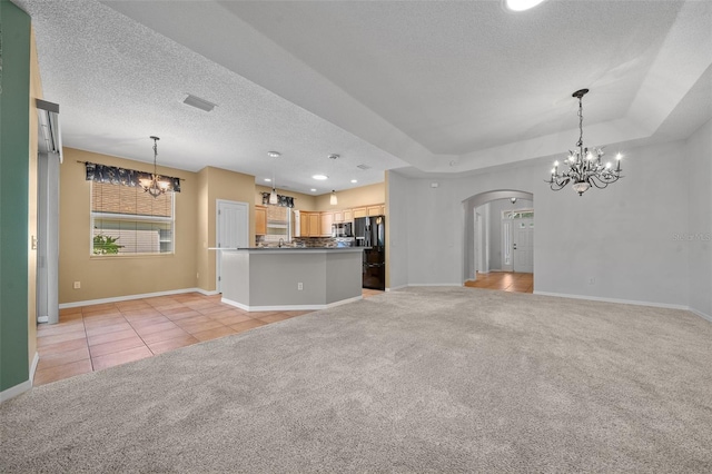 unfurnished living room with light colored carpet, a notable chandelier, and light tile patterned flooring