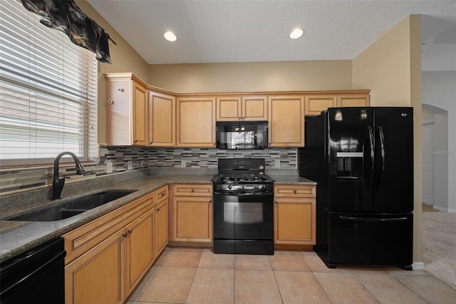 kitchen featuring decorative backsplash, a sink, black appliances, and light tile patterned floors