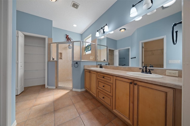 full bathroom featuring a textured ceiling, a stall shower, tile patterned flooring, and a sink