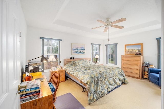 bedroom featuring a tray ceiling, ceiling fan, and light colored carpet