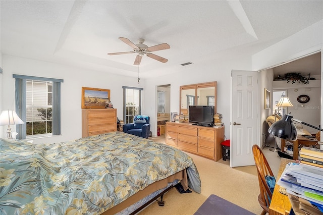 carpeted bedroom featuring ceiling fan and a tray ceiling