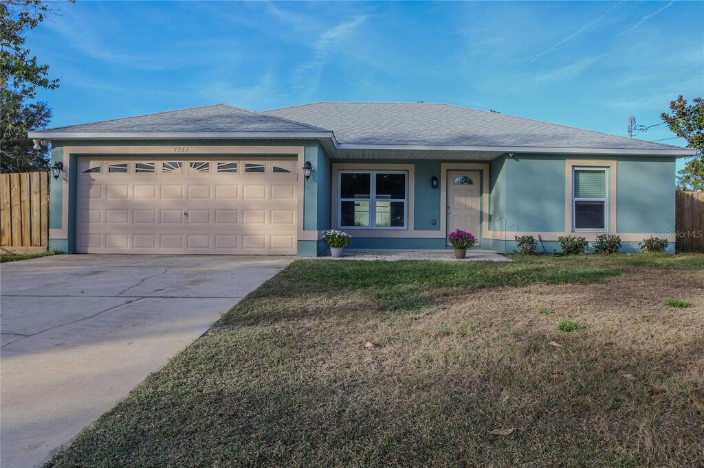 single story home with a front yard, concrete driveway, a garage, and fence