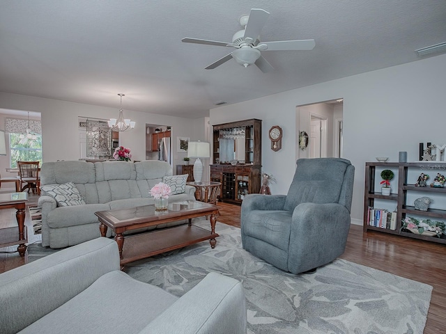 living room with a textured ceiling, ceiling fan with notable chandelier, and wood-type flooring