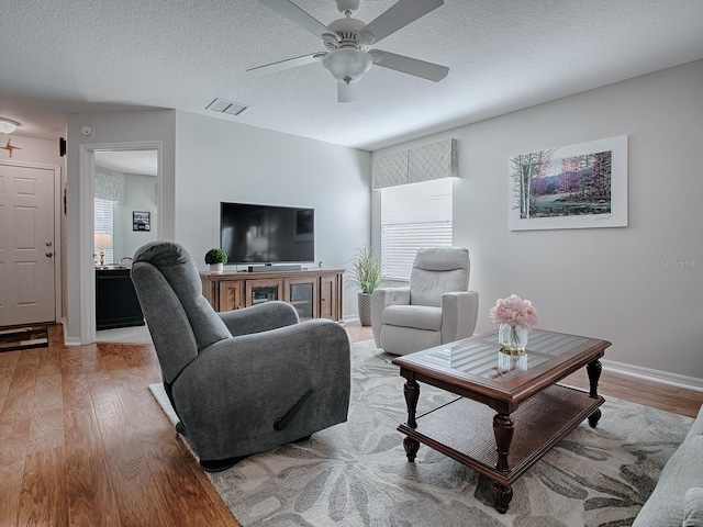 living room with ceiling fan, a healthy amount of sunlight, a textured ceiling, and light hardwood / wood-style flooring