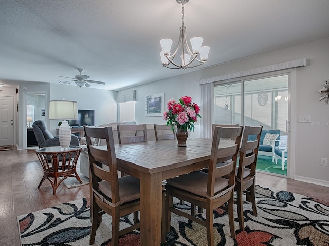 dining area featuring ceiling fan with notable chandelier, plenty of natural light, and wood-type flooring