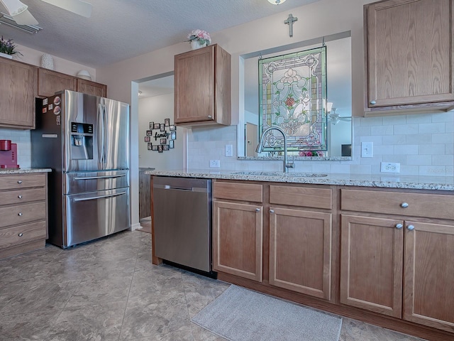 kitchen with light stone countertops, decorative backsplash, appliances with stainless steel finishes, and sink