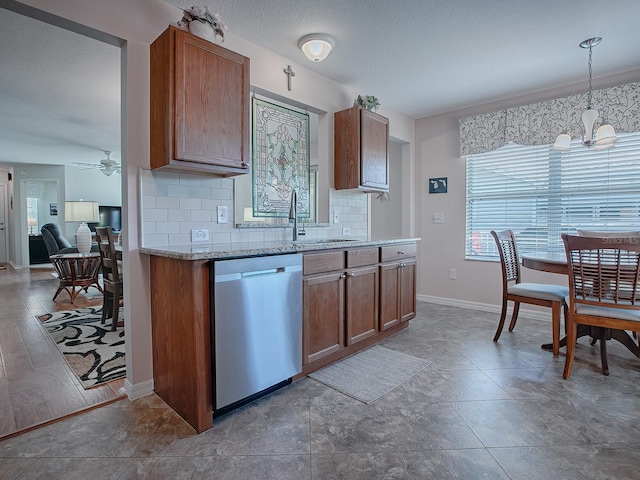 kitchen featuring tasteful backsplash, dishwasher, pendant lighting, ceiling fan with notable chandelier, and sink