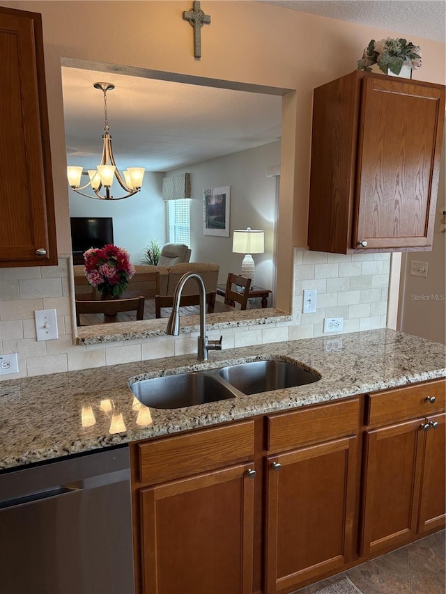 kitchen featuring stainless steel dishwasher, backsplash, sink, and an inviting chandelier